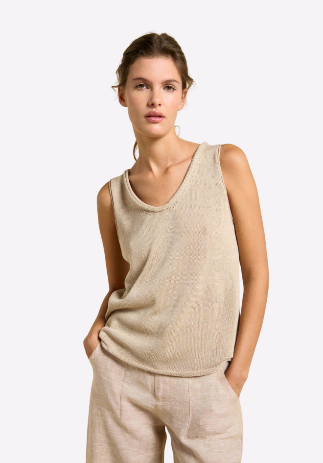 Woman wearing a beige sleeveless top and pants on a white background
