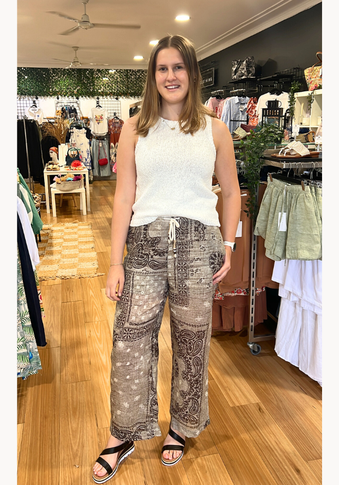 Woman wearing a white sleeveless top and patterned pants in a store setting