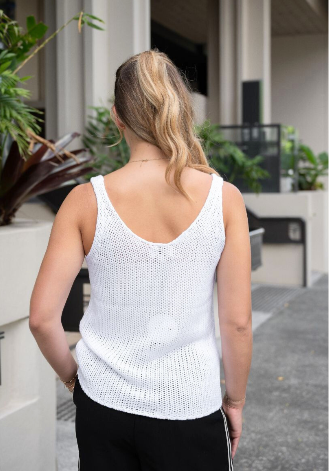 Person wearing a white knitted tank top outdoors