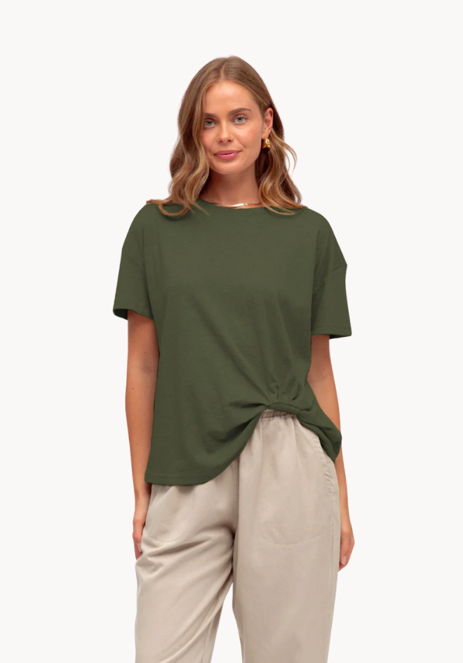 Woman wearing a green t-shirt and beige pants on a white background