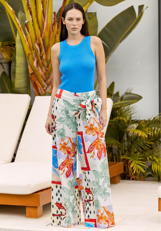 A woman wearing a blue Eva Tank Top, paired with multicolored floral pants.