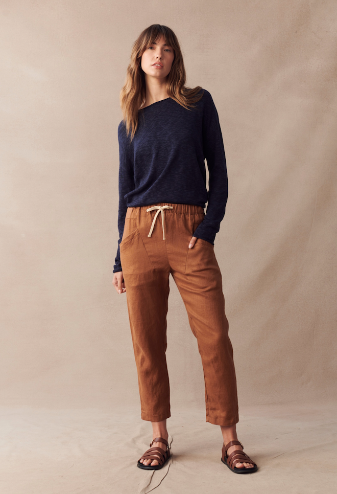 Little Lies Nellie Top Navy — full-length front view of navy long sleeve relaxed knit top with boat neckline, styled with tan drawstring linen pants and brown leather sandals, shop in Australia at Kat and Ko Clothing
