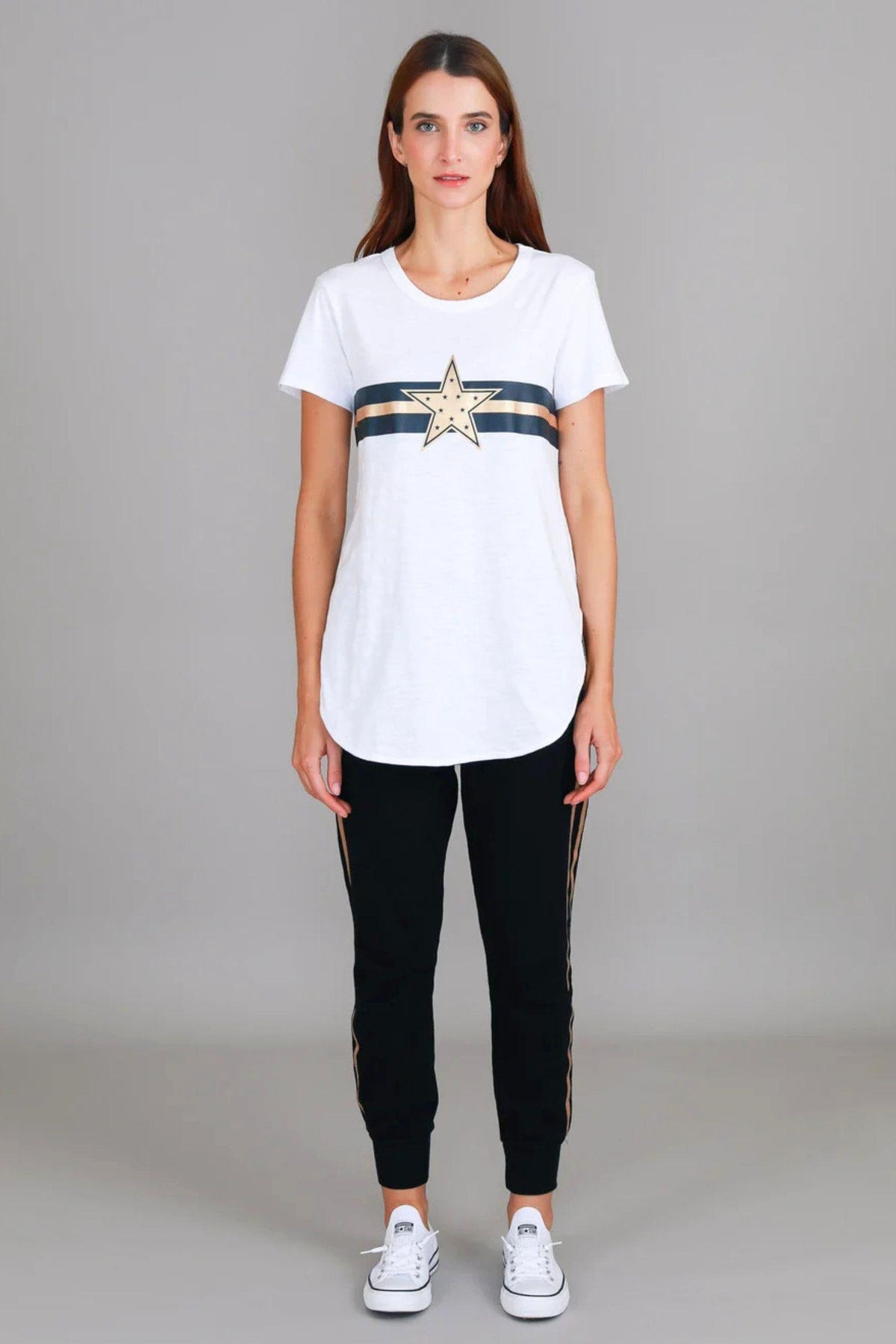 Jill Gold Star White T-Shirt by 3rd Story The Label — full-length front view of white longline tee with gold star and navy stripe graphic print, styled with black and gold side-stripe joggers and white Converse sneakers, shop in Australia at Kat and Ko Clothing