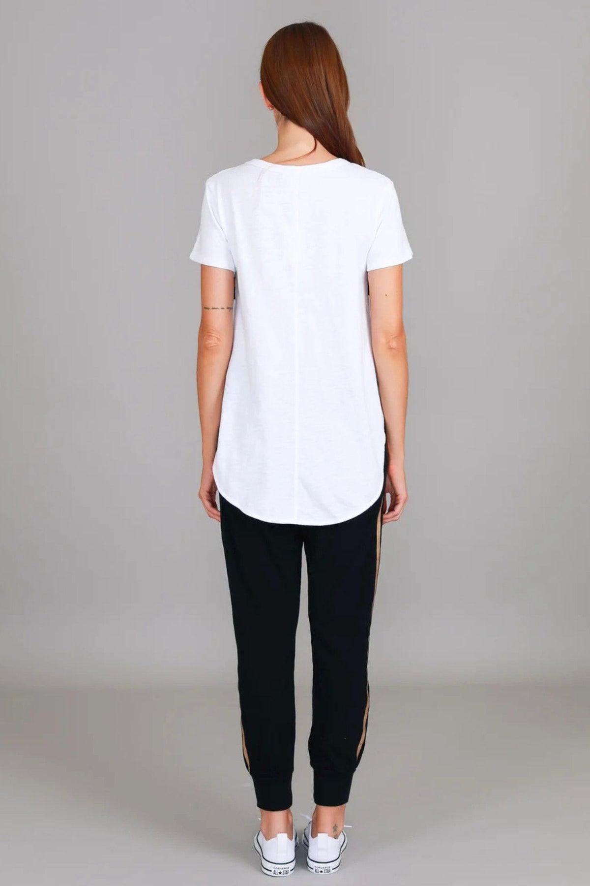 3rd Story The Label Jill Gold Star T-Shirt in White — full-length back view showing the clean longline curved hem and relaxed fit of the white cotton tee, styled with black and gold side-stripe joggers and white Converse sneakers, available in Australia at Kat and Ko Clothing