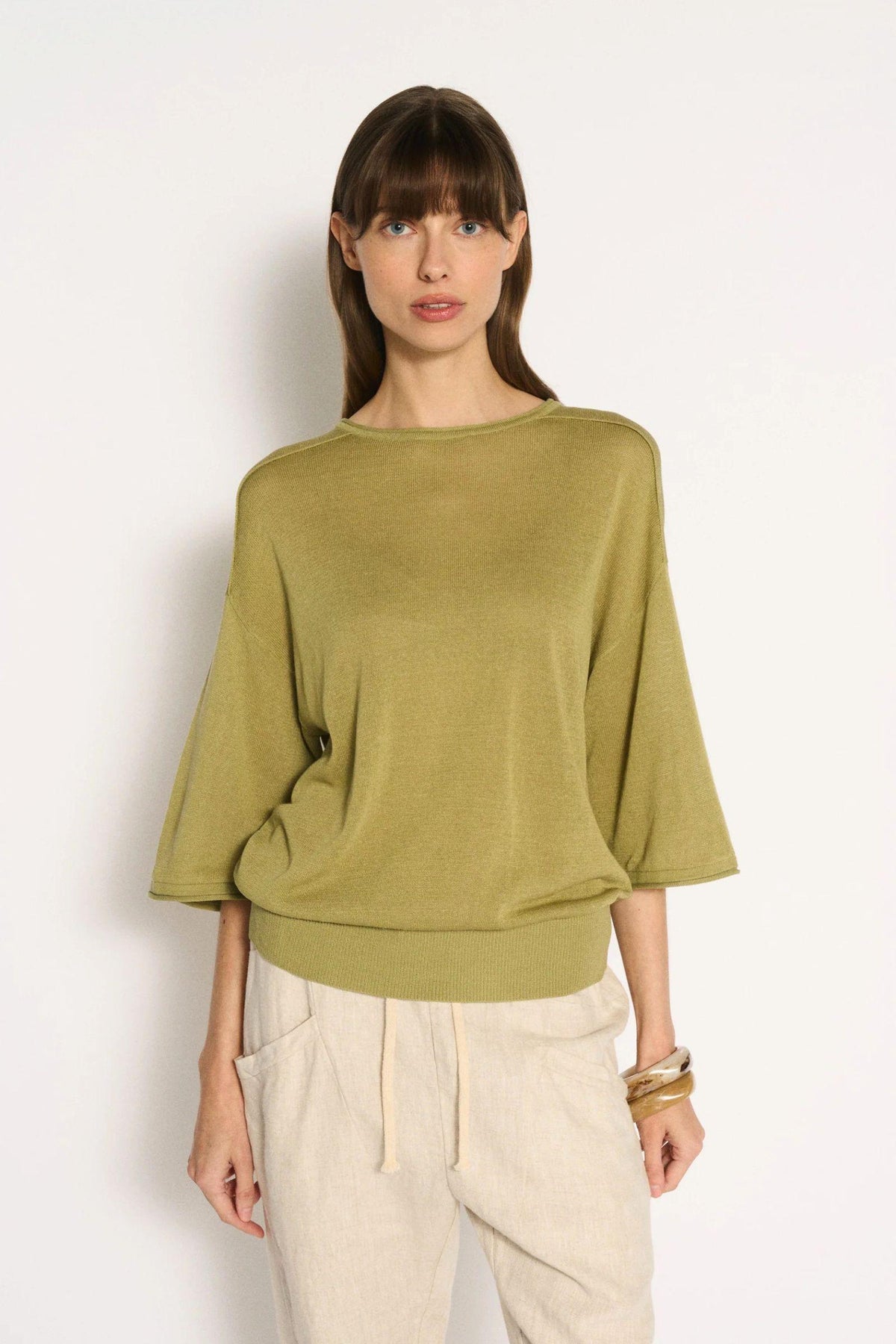 Little Lies Cassie Knit Top in Sage front view showing the wide round neckline and elbow-length sleeves, with cream pants
