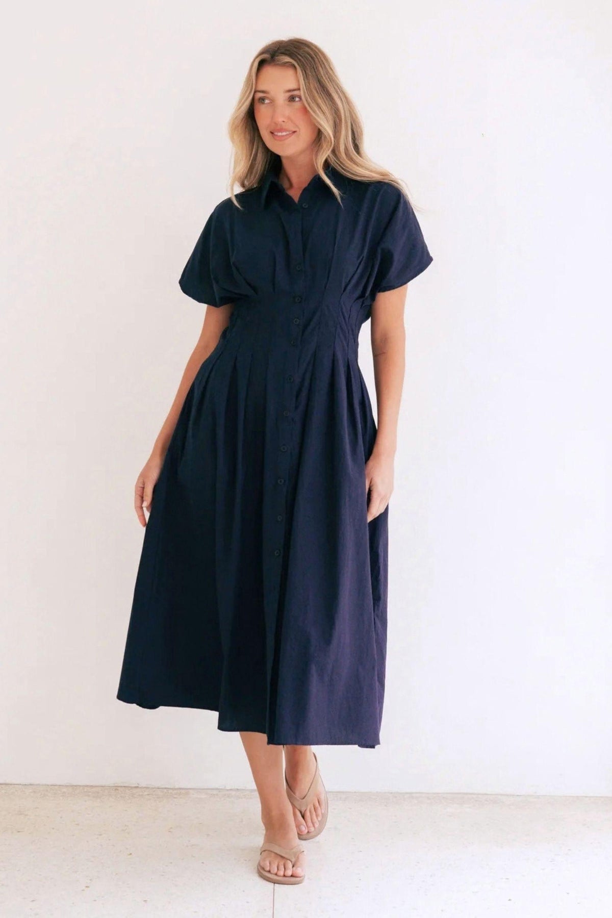 Label of Love Azure Weekend Midi Dress, full-length front view of the navy short-sleeve shirt dress with a defined waist and midi skirt, styled with tan sandals. Available in Australia at Kat and Ko Clothing.
