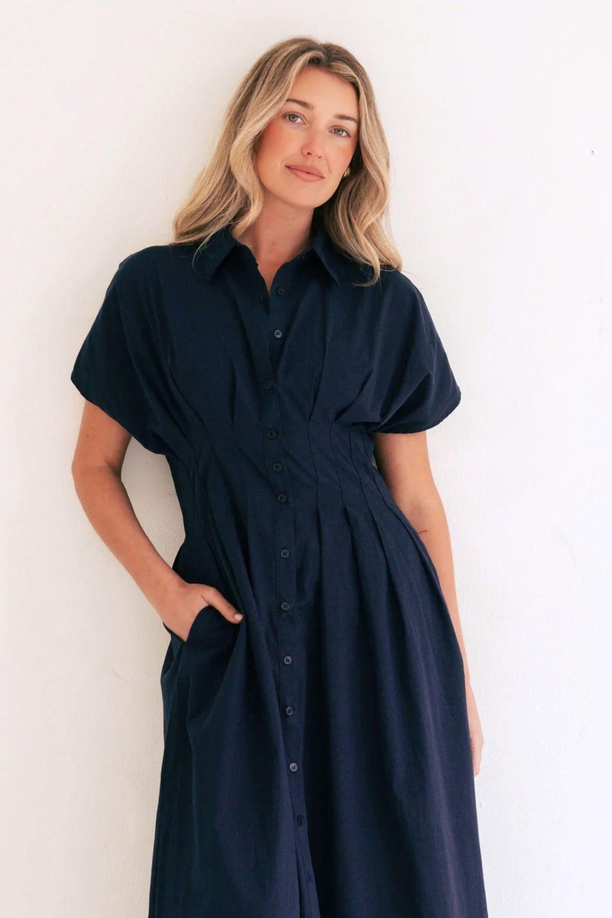 Label of Love Azure Weekend Midi Dress, close front view showing the navy dress's collar, button front, pleated waist and side pocket. Available in Australia at Kat and Ko Clothing.
