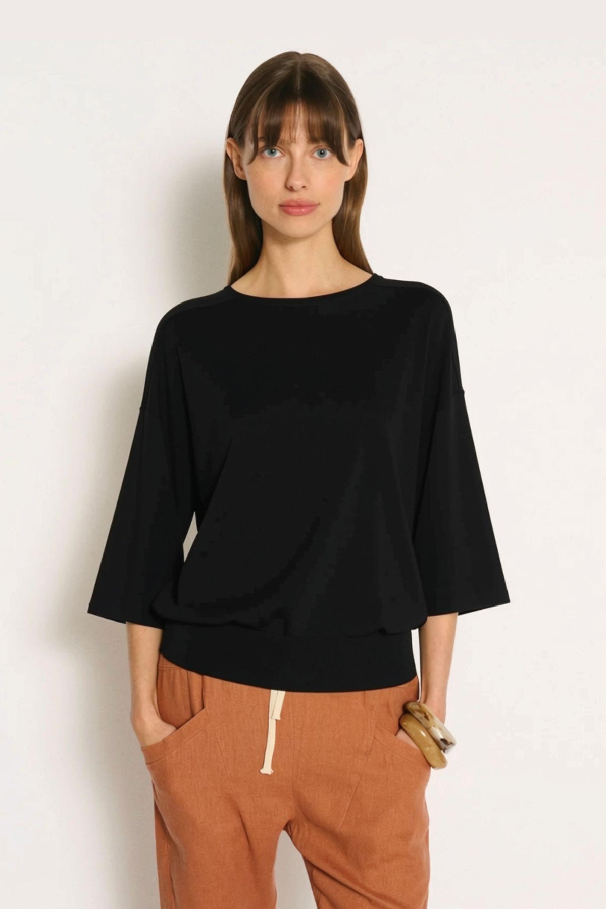 Little Lies Cassie Knit Top in Black front view of the relaxed fit, styled with rust drawstring pants