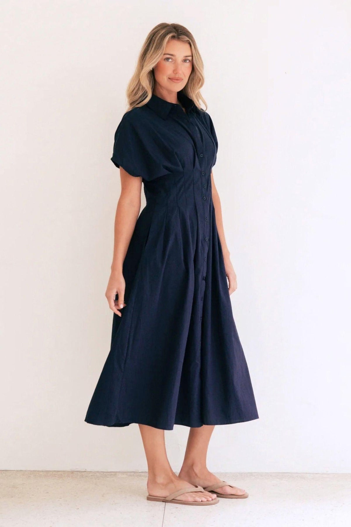 Azure Weekend Midi Dress by Label of Love, angled front view of the navy collared dress with short sleeves and a pleated skirt, styled with tan flat sandals. Available in Australia at Kat and Ko Clothing.