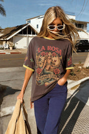La Rosa Tee in Lemon by Coco Cartel — lifestyle street shot of oversized charcoal graphic tee with La Rosa Mermaid Club print and yellow ringer trim, styled with navy jeans and a straw bag, shop in Australia at Kat and Ko Clothing