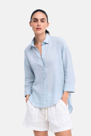 Little Lies Boyfriend Shirt in Chambray Blue linen worn with white shorts, front view