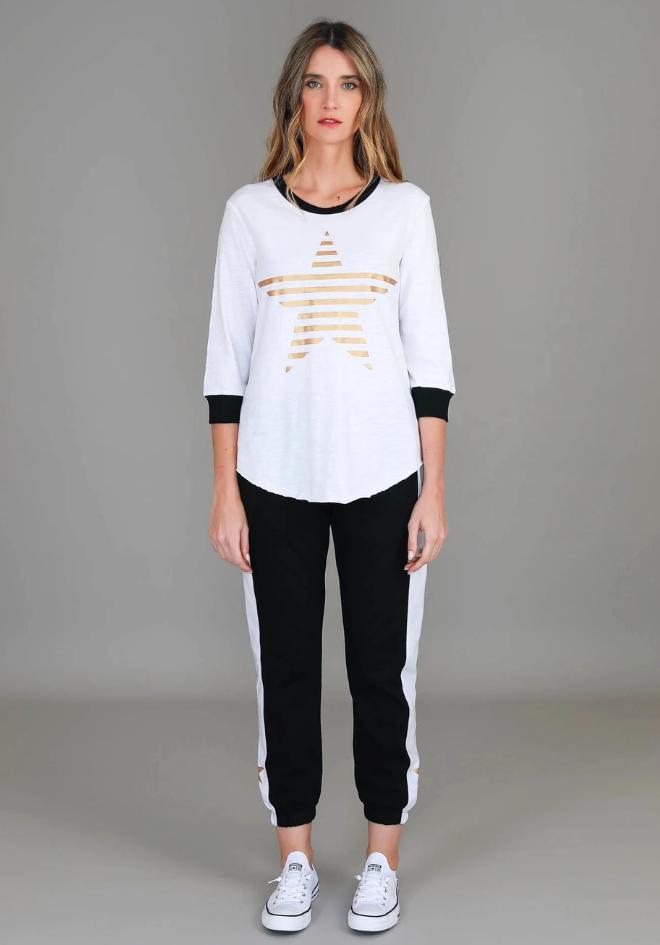 3rd Story The Label Sammie 3/4 Star T Shirt — full-length front view of white relaxed fit tee with gold metallic star print and curved hem, styled as a matching set with black and white stripe joggers and white sneakers, shop in Australia at Kat and Ko Clothing