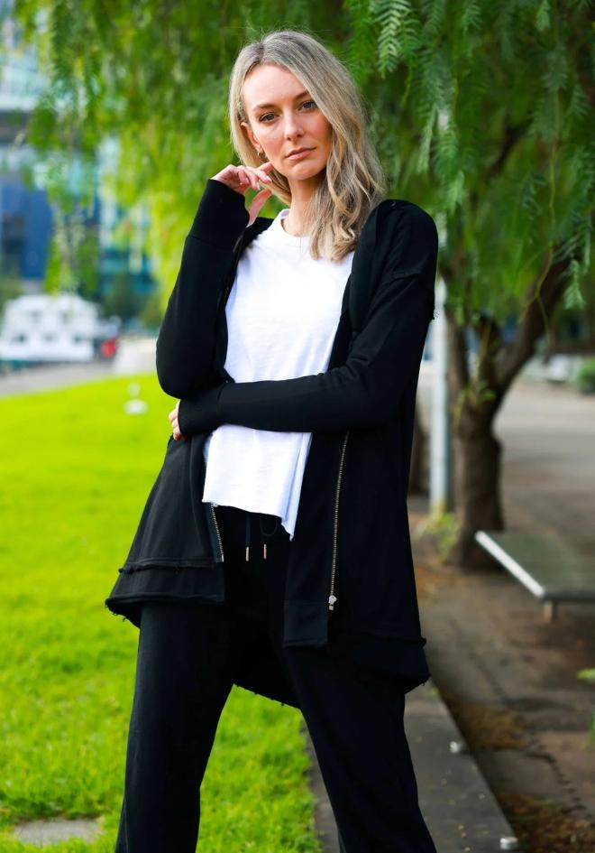 Charlie Jacket in Black by 3rd Story The Label — lifestyle front view of oversized black French Terry hooded zip jacket with raw-edge hem and thumb-hole cuffs, layered over white tee and black pants, available in Australia at Kat and Ko Clothing