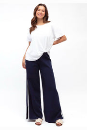 Label of Love Simba Knit Pant in Navy front view with white side stripe, worn with a white tee and sandals