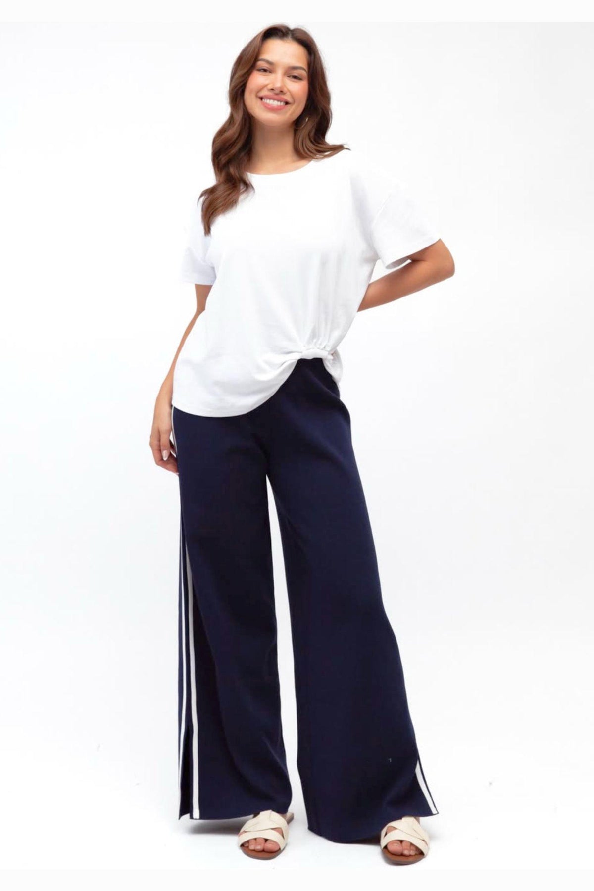 Label of Love Simba Knit Pant in Navy front view with white side stripe, worn with a white tee and sandals