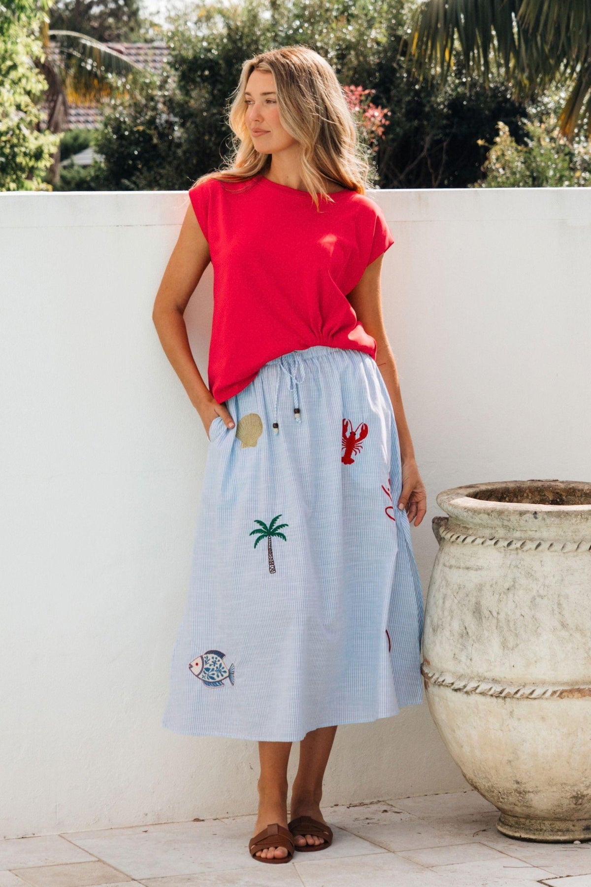 Label of Love Mariniere Embroidered Skirt in Blue Stripe, side view of the midi length with a red top
