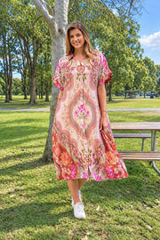 Fionn Midi Dress by Boho Australia — front view of the pink patterned midi dress with a fabric belt, styled with white sneakers in a park, available in Australia at Kat and Ko Clothing