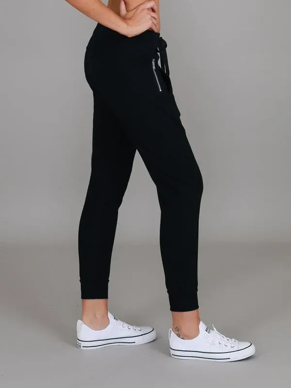 Byron Jogger Black by 3rd Story The Label — side view of black slim-fit jogger with silver zip pocket detail and tapered ribbed ankle cuff, styled with white sneakers, available in Australia at Kat and Ko Clothing