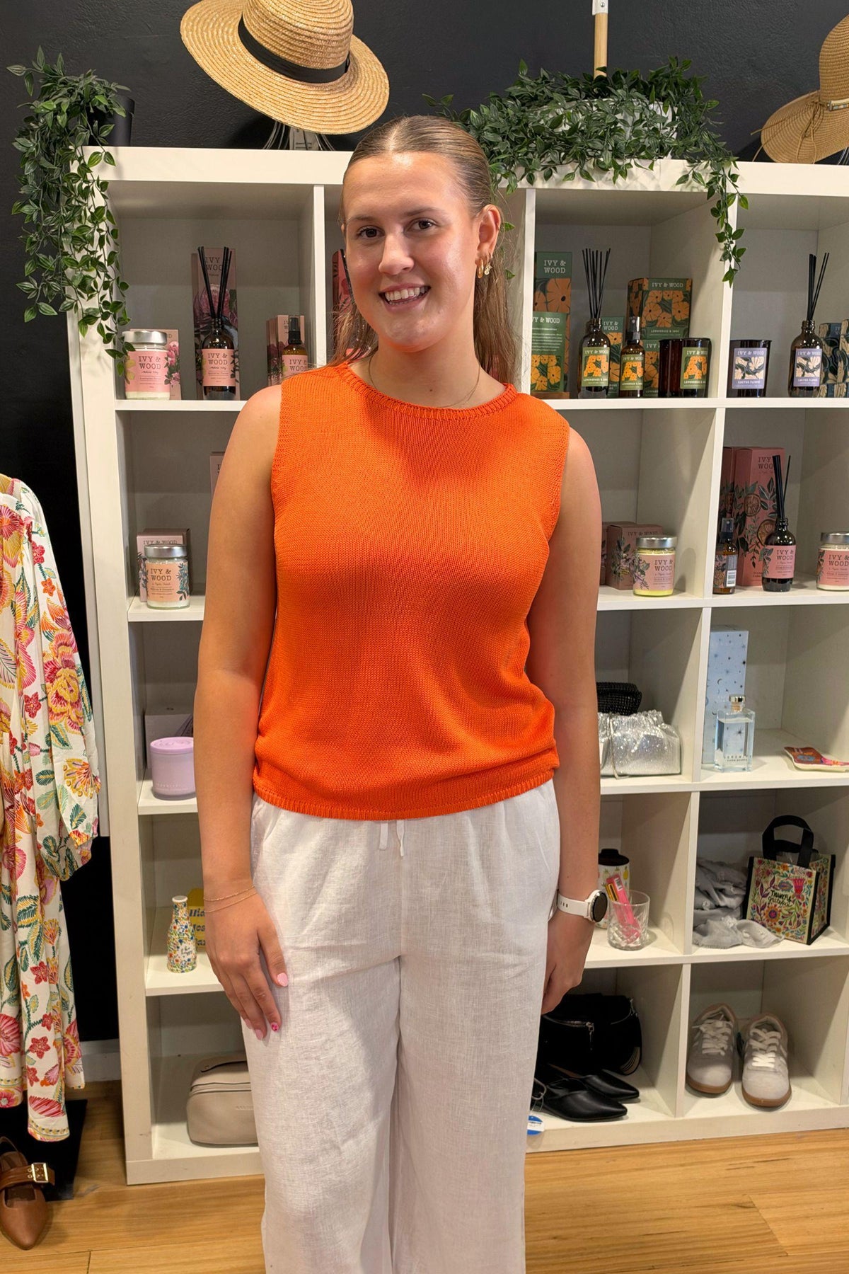 Little Lies Spring Tank in Vivid Orange slightly angled view, tucked into white linen pants