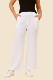 Stella Linen Pants in White by Bottega Moda — front view of wide-leg white Italian linen pants with elastic waistband and side pockets, styled with a black tank top and white sneakers, available in Australia at Kat and Ko Clothing