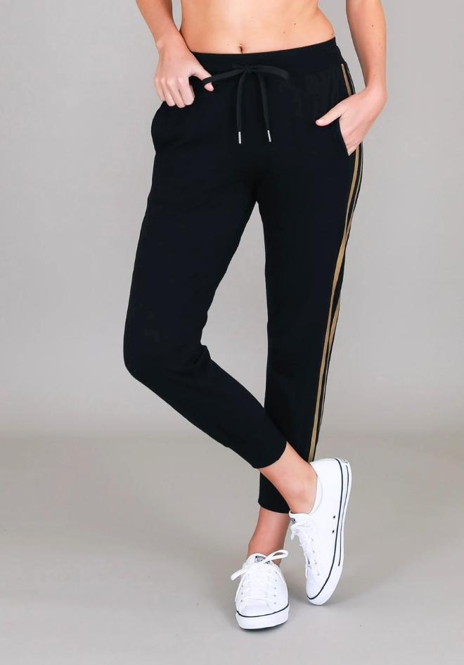 Gabby Stripe Jogger Black 3rd Story The Label — cropped front view of black cotton jersey jogger with drawstring elastic waist, side pockets and gold metallic stripe detail, styled with white sneakers, available in Australia at Kat and Ko Clothing