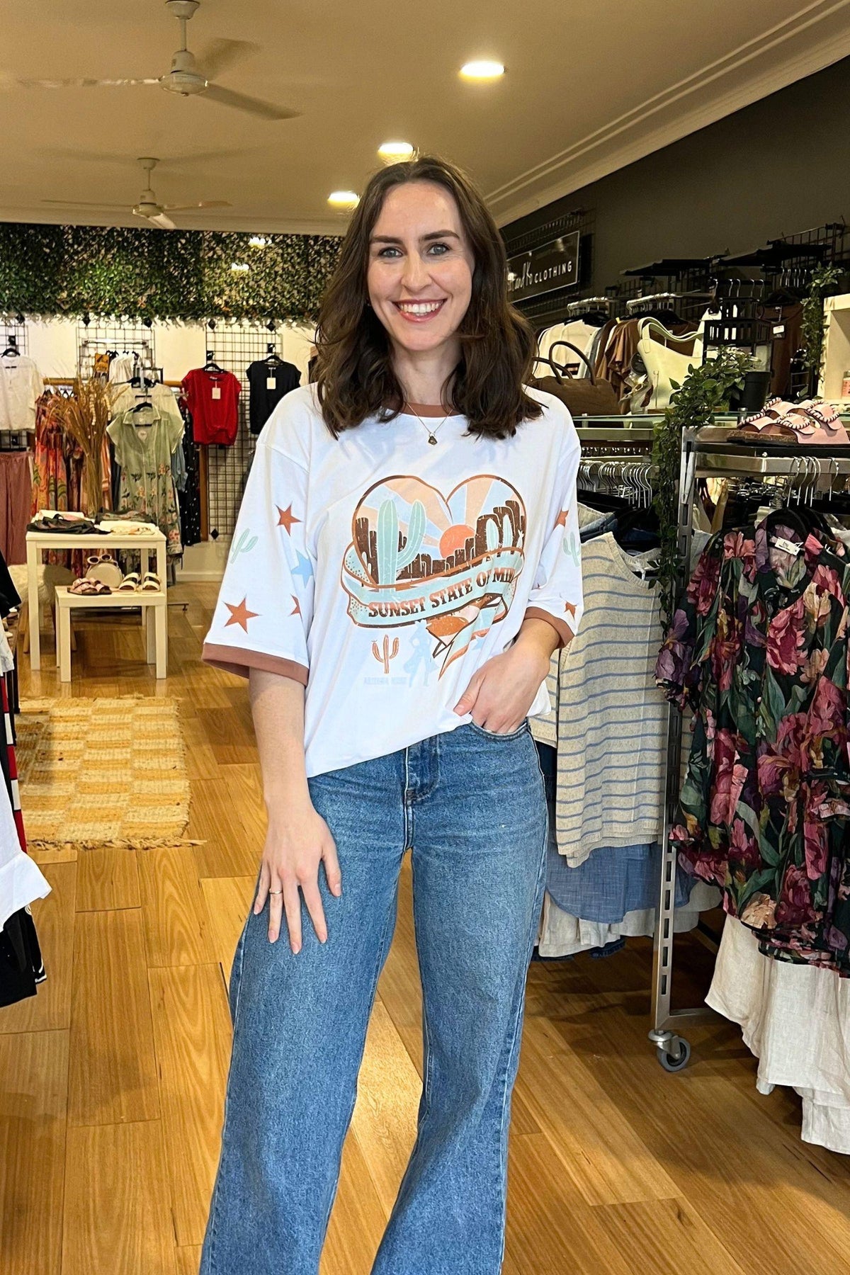 Coco Cartel Sunset State of Mind Tee - White, full-length view of the white graphic tee worn loose with blue jeans, available in Australia at Kat and Ko Clothing