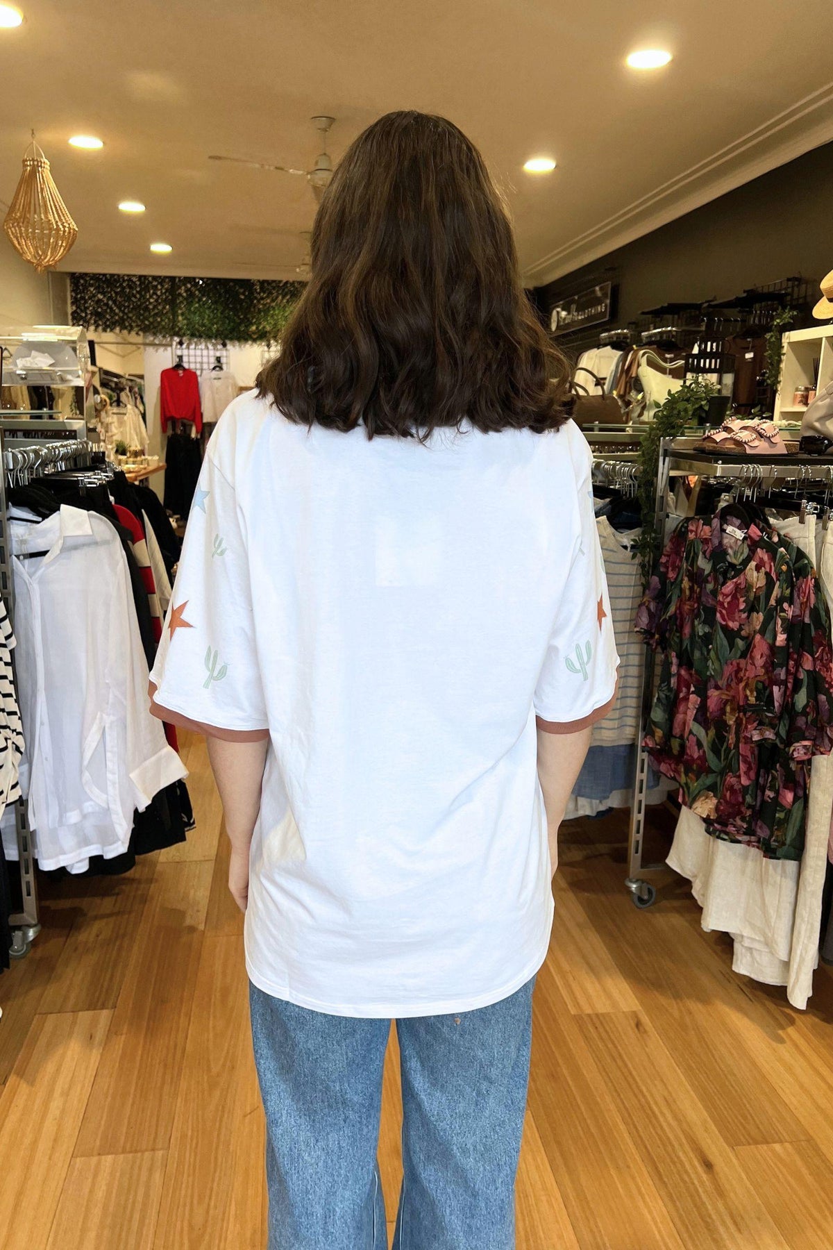Coco Cartel Sunset State of Mind Tee - White, back view of the oversized white tee styled with blue jeans, available in Australia at Kat and Ko Clothing