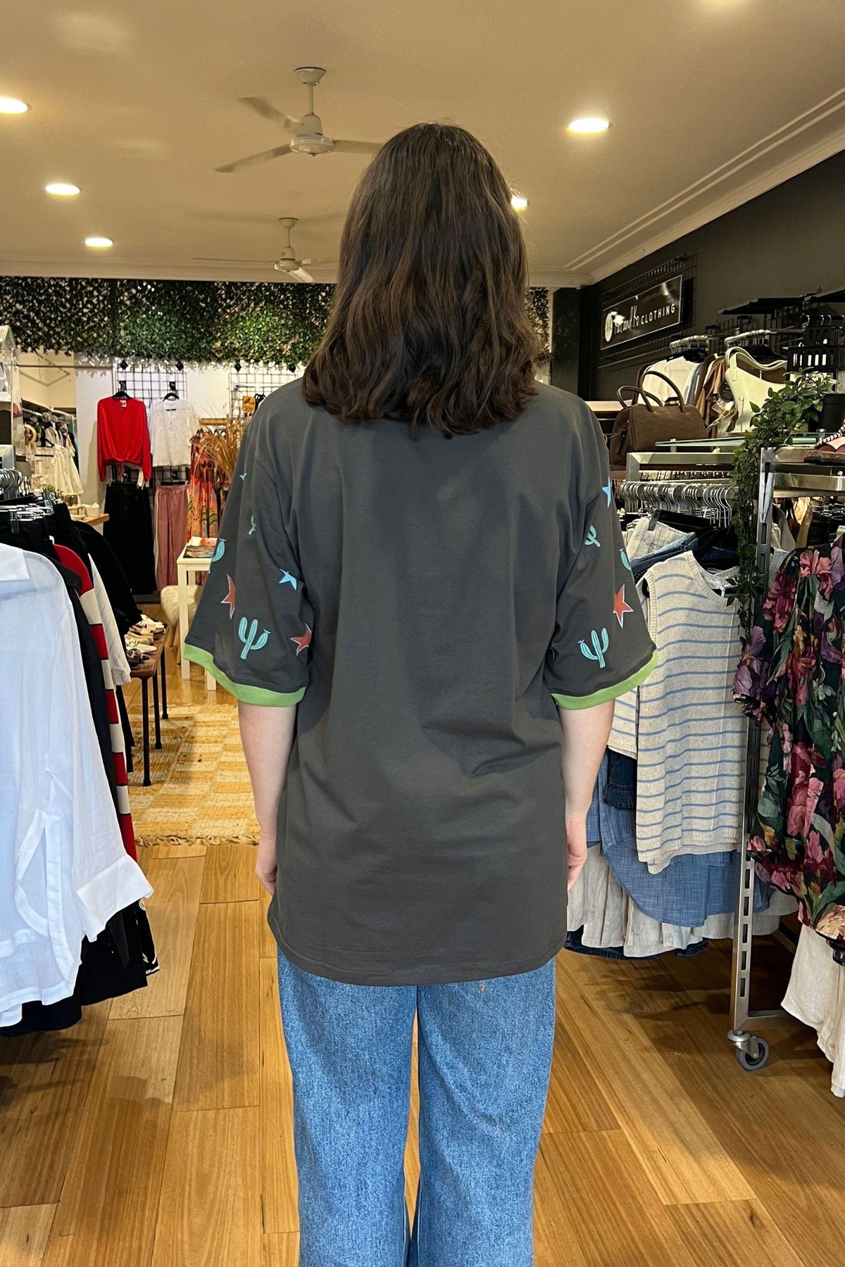 Sunset State of Mind Tee - Charcoal, Coco Cartel, back view of the oversized charcoal tee styled with blue jeans, available in Australia at Kat and Ko Clothing