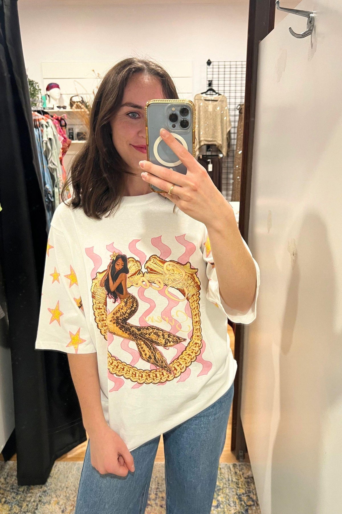 Coco Cartel Siren Tee - White, mirror selfie showing the siren-inspired front graphic and loose fit, styled with blue jeans in Australia at Kat and Ko Clothing