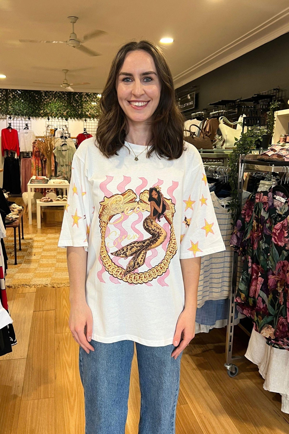 Siren Tee - White by Coco Cartel, front view of the oversized white tee with siren-inspired graphic and star-print sleeves, styled with blue jeans in Australia at Kat and Ko Clothing