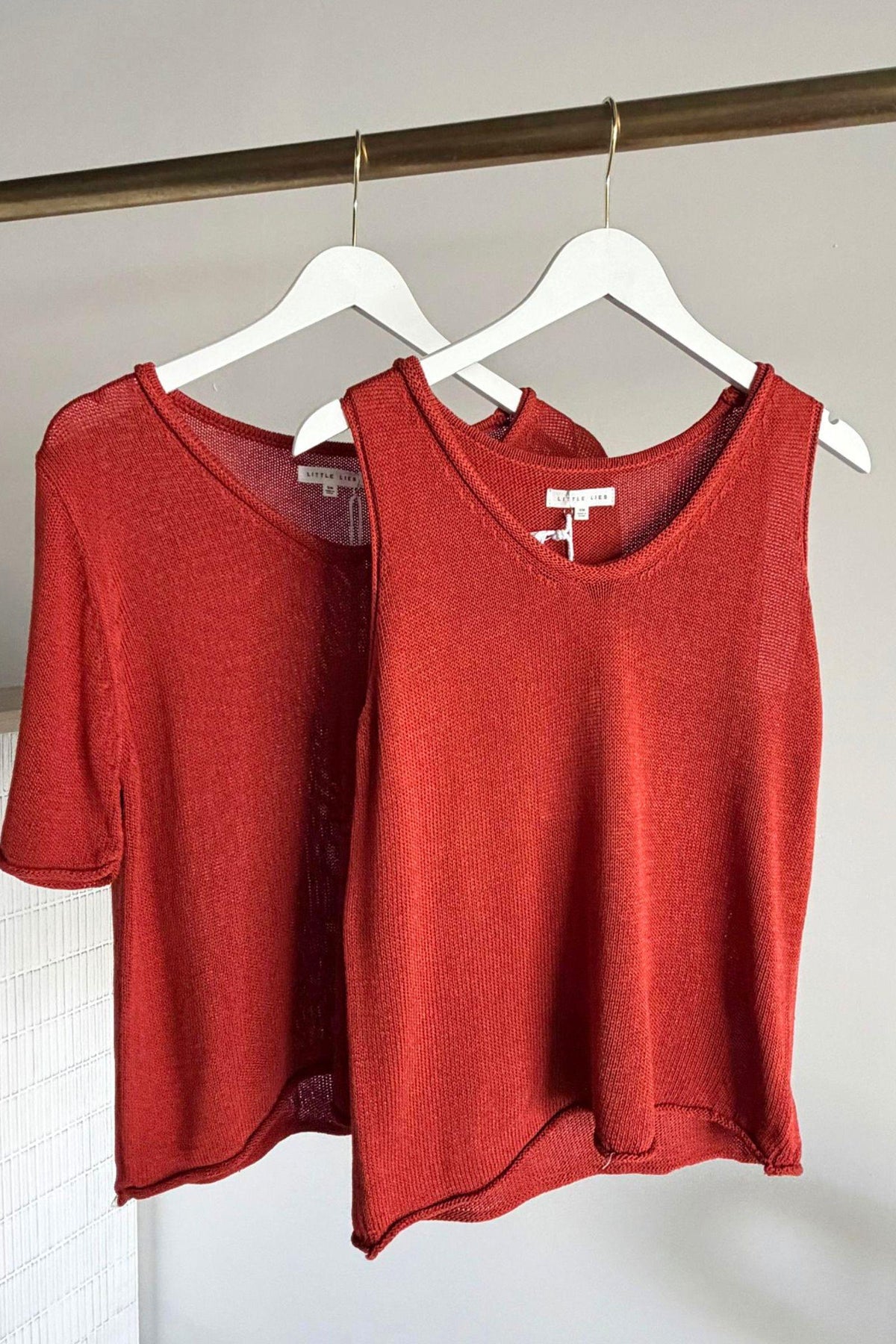 Little Lies Scoop Neck Spring Tee and Scoop Spring Tank in Earthy Red hanging together, tank layered in front