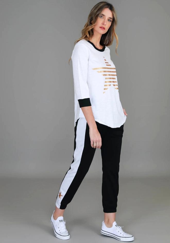 Sammie 3/4 Star T Shirt 3rd Story The Label — angled side view of white cotton jersey tee with gold star print and 3/4 sleeves with contrast black cuffs, styled with black and white stripe joggers and white sneakers, available in Australia at Kat and Ko Clothing