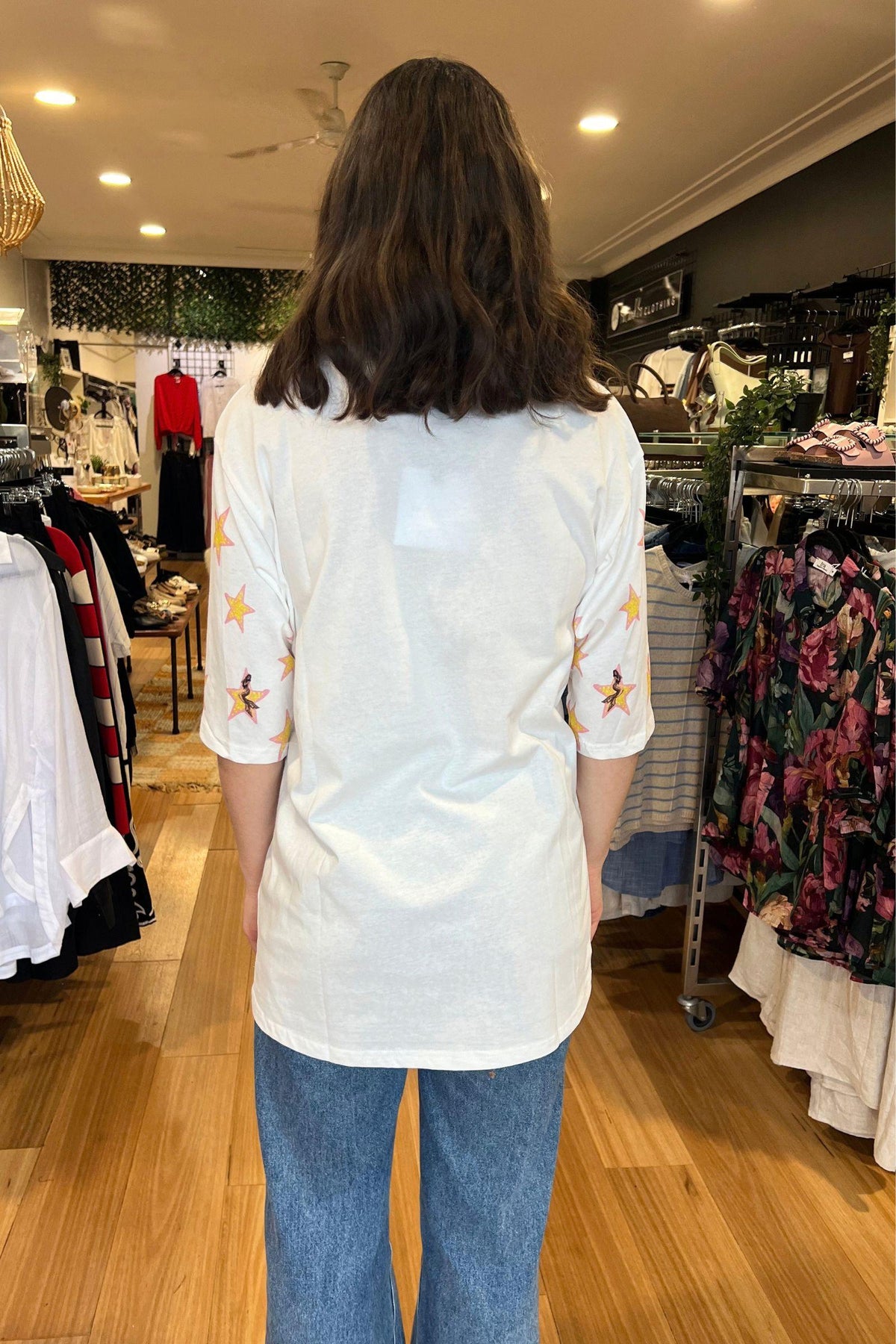 Coco Cartel Siren Tee - White, back view of the oversized white tee with star-print sleeves, styled with blue jeans in Australia at Kat and Ko Clothing