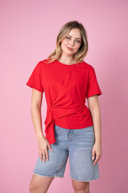 Fria The Label Ellery Tee in Red, front view showing the asymmetrical hem, styled with light denim shorts