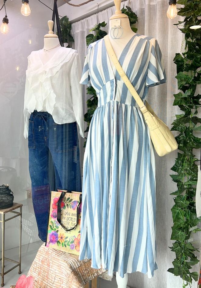 Miracle Della Dress Blue Stripe — in-store mannequin display of blue and white stripe midi dress with V-neckline, flutter sleeves and gathered skirt, styled with a yellow crossbody bag at Kat and Ko Clothing Australia