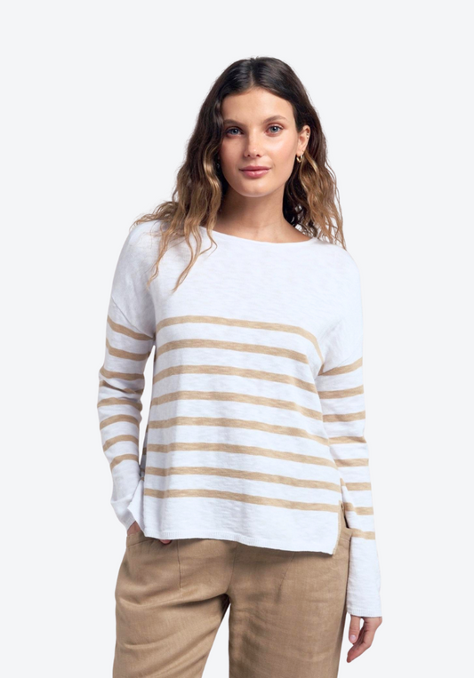 Woman wearing a white sweater with gold stripes and beige pants on a white background