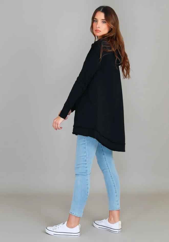 Charlie Jacket Black by 3rd Story The Label — back side profile of longline black hooded jacket with raw-edge hi-lo hem, styled with light denim jeans and white sneakers, available in Australia at Kat and Ko Clothing