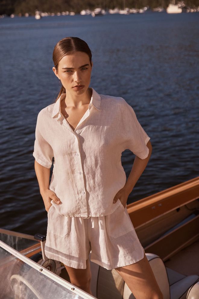 Woman in light clothing standing on a boat with water in the background