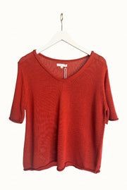 Little Lies Scoop Neck Spring Tee in Earthy Red front view on a hanger, showing the short sleeves and rolled edges