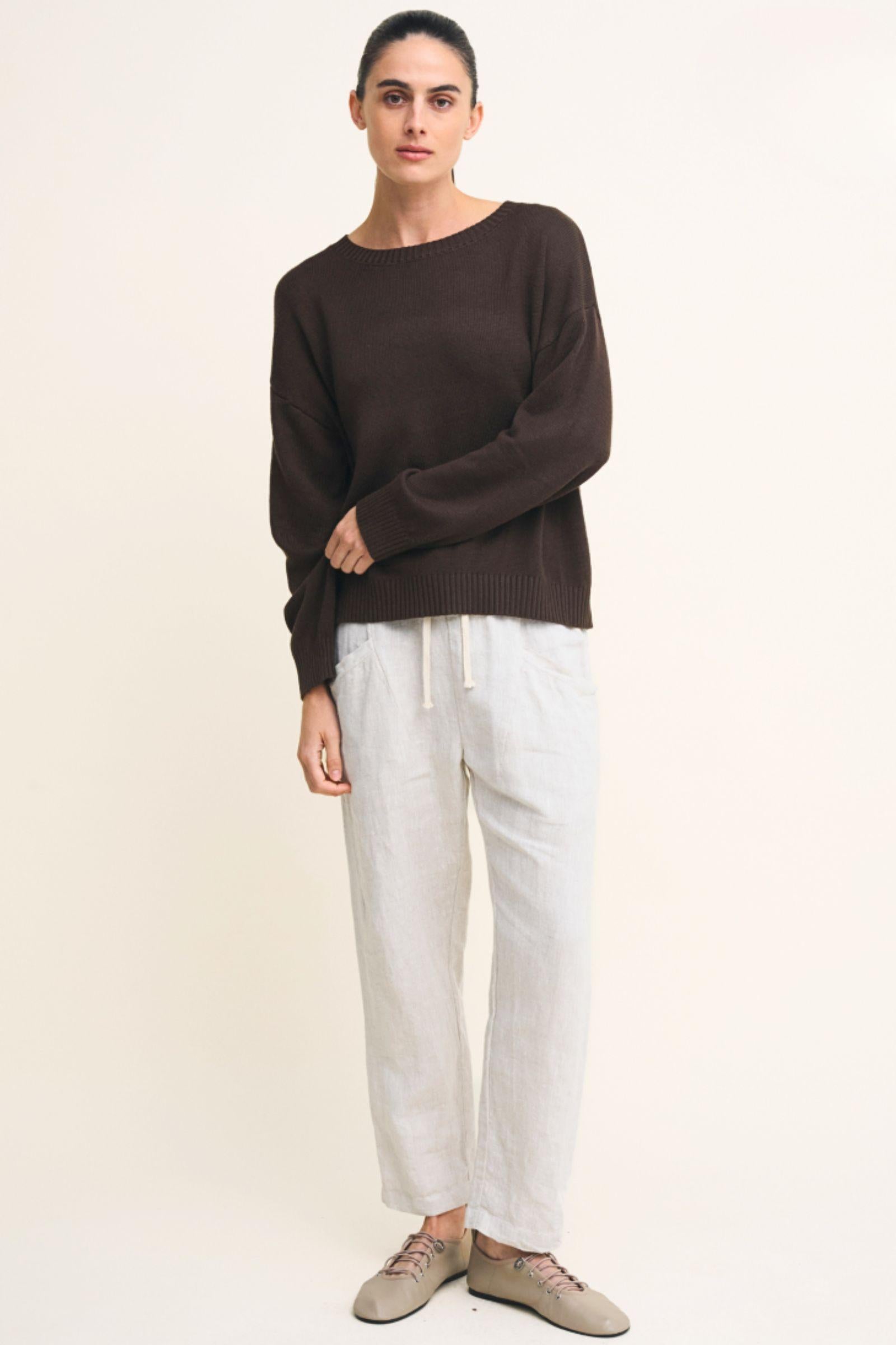 Victoria Jumper Chocolate Little Lies — full-length front view of chocolate brown relaxed boat neck knit jumper styled with white linen drawstring pants and taupe loafers, available in Australia at Kat and Ko Clothing