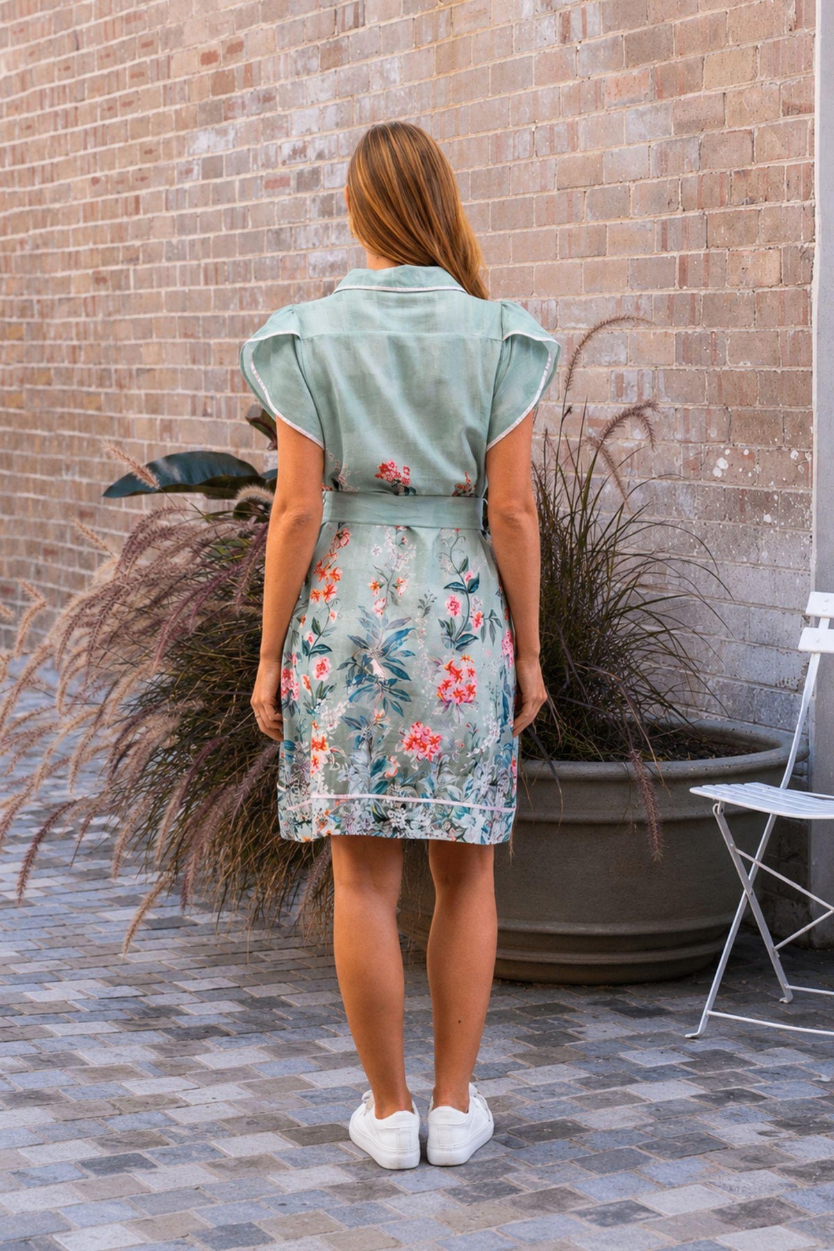 Sanders Dress by Boho Australia — back view of the sage floral dress showing the short silhouette, tulip sleeves and self-fabric belt, styled with white sneakers, available in Australia at Kat and Ko Clothing