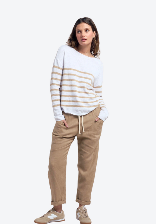 Woman wearing a white and gold striped sweater with beige pants on a white background