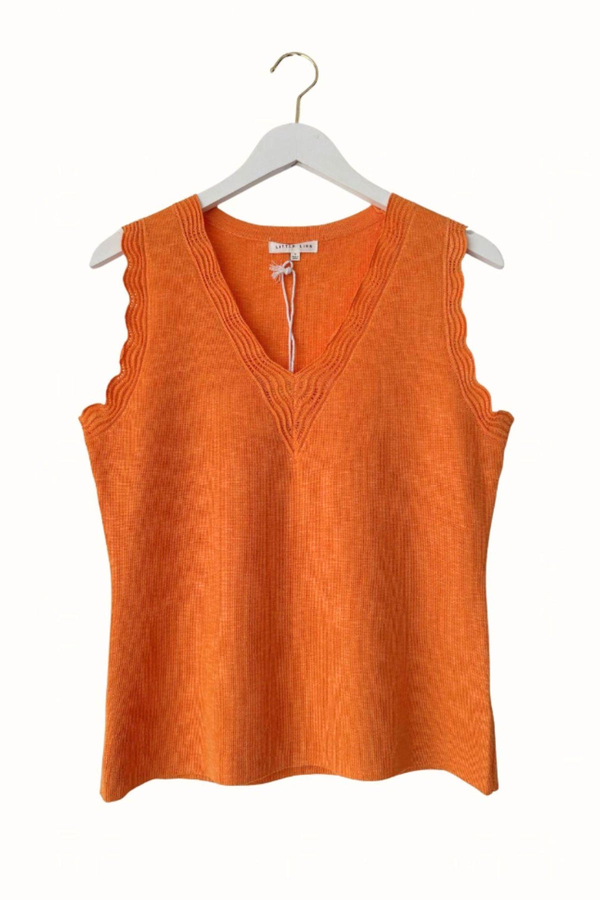 Little Lies Leila Knitted Top in Orange on a hanger showing the V-neckline and scalloped armhole edging