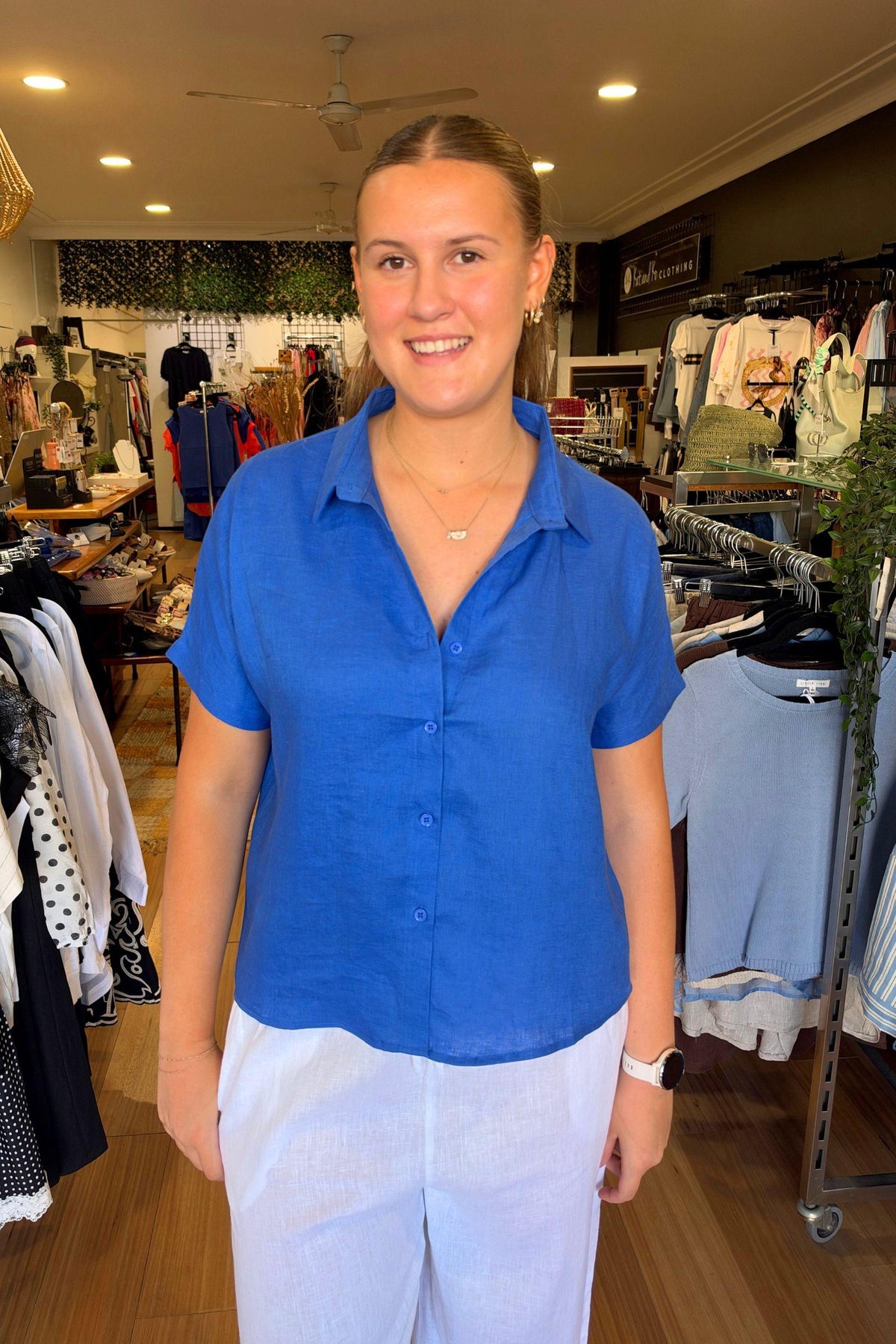 Little Lies Bronte Shirt in Cobalt front view showing the collar and short sleeves, worn with white pants