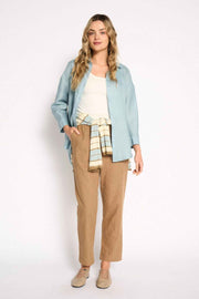 Full-length view of the Little Lies Boyfriend Shirt in Aqua Haze with tan trousers and a striped knit at the waist
