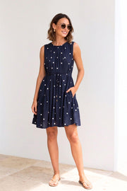 Midnight Spot Midi Dress by Label of Love — full-length front view of navy and white polka dot sleeveless tiered dress with drawstring waist, styled with tan slides and sunglasses, shop in Australia at Kat and Ko Clothing