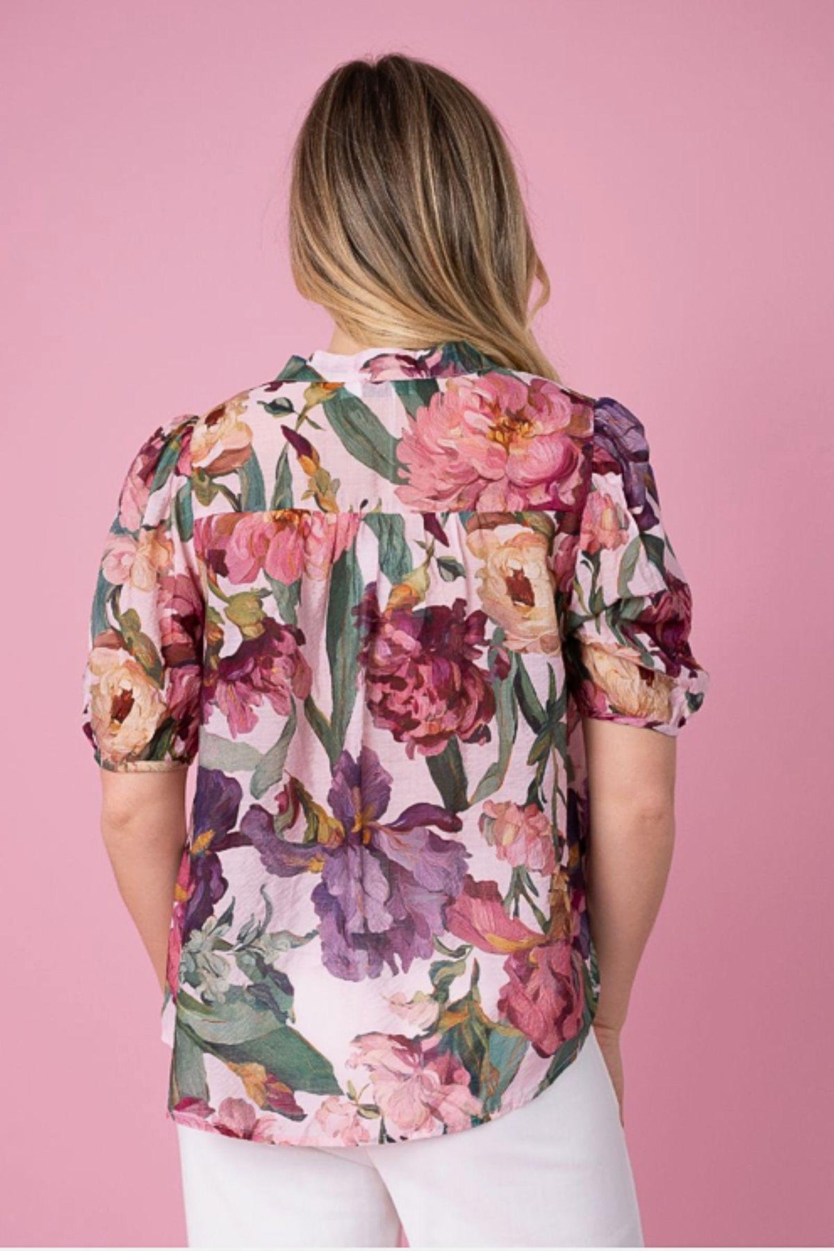Fria The Label Floral Flare Blouse — back view of the relaxed pink floral blouse and short sleeves, styled with white trousers, available in Australia at Kat and Ko Clothing
