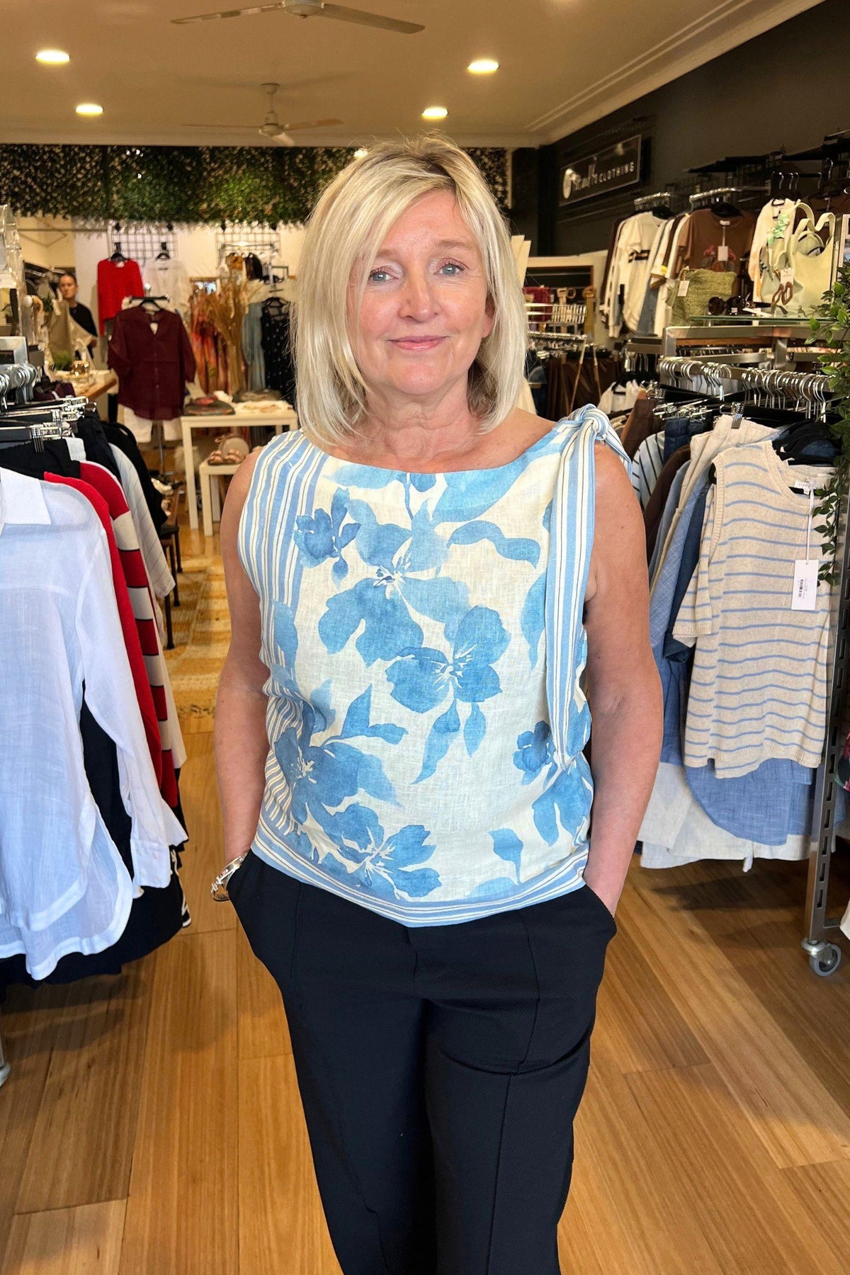 Delphine Linen Cami by Little Lies — in-store view of model wearing blue floral print cami with tie neckline, styled with navy pants, shop in Australia at Kat and Ko Clothing