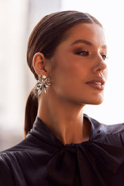 A woman wearing Hollywood Boulevarde stud earrings, which are large and have a floral pattern, displayed from a close-up angle.