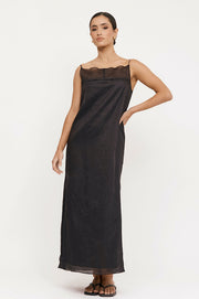 A model wearing a black, sleeveless, square neckline, thin straps, and side splits river dress.